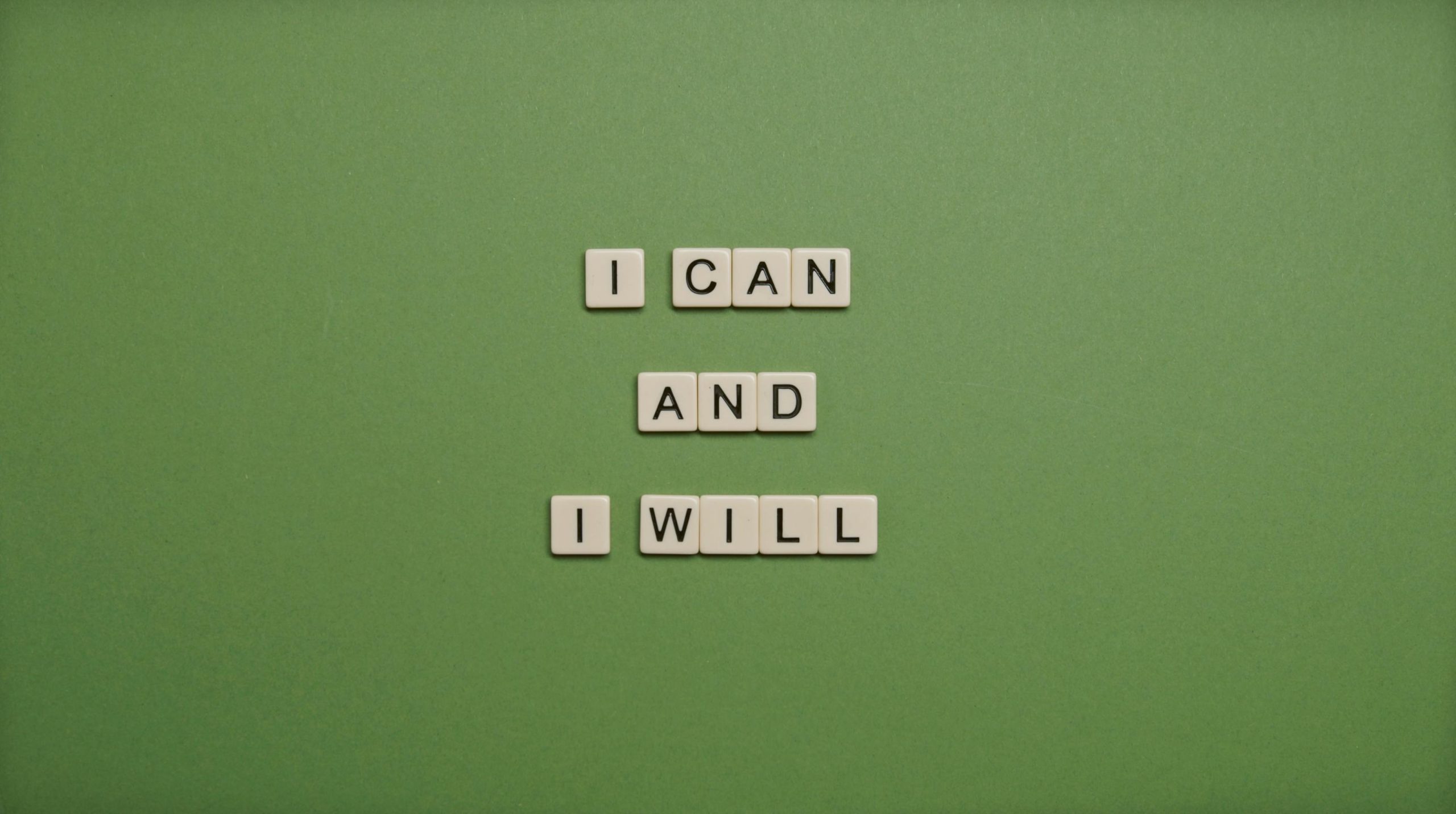 Inspirational message 'I Can and I Will' spelled with tile letters on a green background.